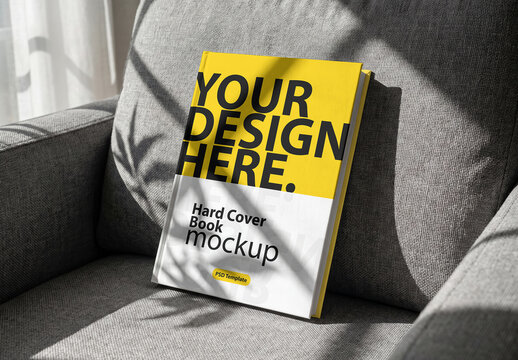 Hardcover Book Mockup stands on a gray armchair