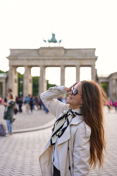 Smiling woman in sunglasses posing before Brandenburg Gate in Berlin