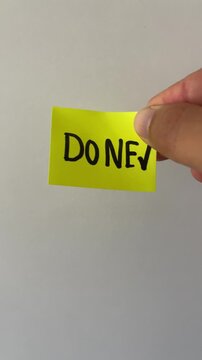 Hand holding done checkmark sticky note on white background