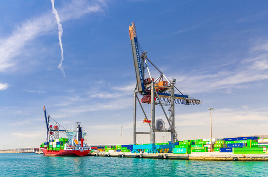Alicante, Spain, June 1, 2025: Port crane, cargo ship and many containers on the pier in Port of Alicante Puerto de Alicante seaport in Alicante city, Bahia Alicante bay Mediterranean Sea water