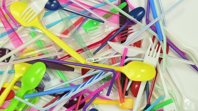 Plastic waste. Disposable single-use plastic drinking straws, forks, spoons, knifes that cause pollution of the environment.