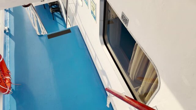 A steep ladder leads down to a bright blue deck on a cruise ship sailing Lake Ladoga. A red life ring hangs securely on the wall. The exciting journey brings a feeling of adventure and wonder.