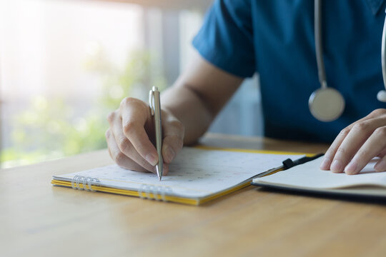 close up expertise doctor hand use pen to write or note on calendar to make appointment date and time in office at clinic for health  lifestyle concept
