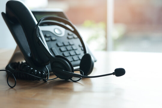 close up soft focus on headset with telephone devices at office desk for customer service support concept