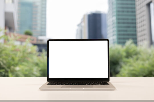 close up blank white screen display of laptop computer on table in office building with garden scene for add content of design banner,website or template or online shopping e-commerce concept