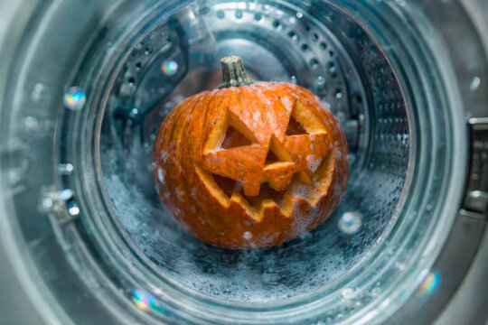 A Jack-o'-lantern pumpkin in a washing machine. A funny Halloween scene.