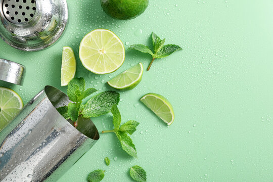 Shaker, limes and mint on green background, flat lay. Space for text