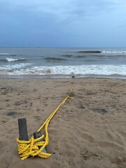 Yellow rope tied to wooden posts on the beach and Scenic Vizag Rushikonda Beach Coastline Landscape Shot During Cloudy and Rainy Weather in the Evening at Rushikonda, Visakhapatnam © AI Digital Art