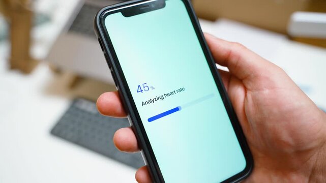 Hand holding smartphone with health app analyzing heart rate and showing normal bpm result