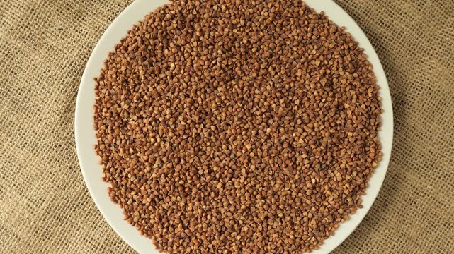 White plate of roasted buckwheat groats rotating