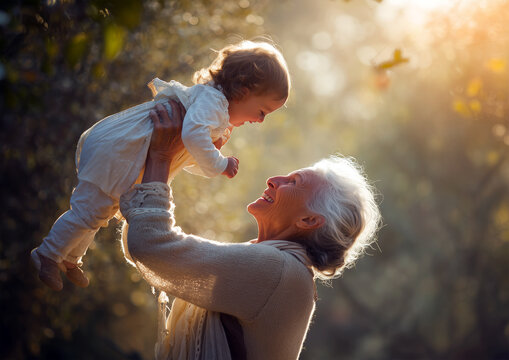 Elderly woman joyfully lifting a toddler in the air outdoors. Playful, loving, and warm scene in a park or garden. Realistic and cinematic moment. Hands not visible.
