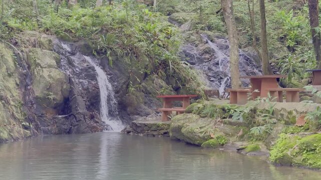 Kathu Dam waterfall water gently flowing down the rocks surrounded by lush green trees flowers and tables Patong on the Island of Phuket Thailand
