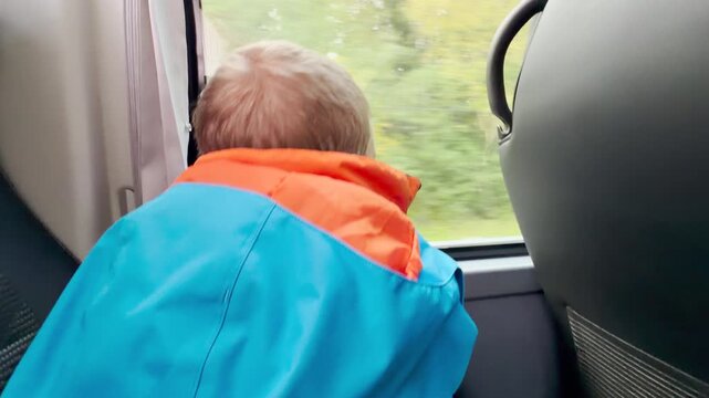 A young boy looks out a bus window while traveling through Karelia. The cozy ride brings a calm and joyful feeling of wonder.
