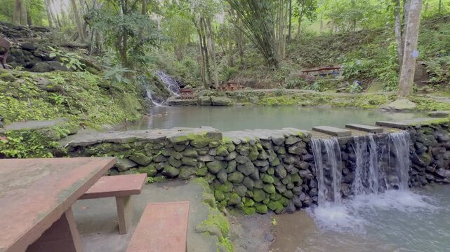 Kathu Dam waterfall water gently flowing down the rocks surrounded by lush green trees flowers and tables Patong on the Island of Phuket Thailand