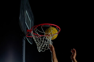 A man performs a slam dunk on a basketball court at night under the glare of bright outdoor lights © nazariykarkhut