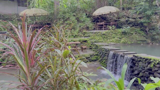 Kathu Dam waterfall water gently flowing down the rocks surrounded by lush green trees flowers and tables Patong on the Island of Phuket Thailand
