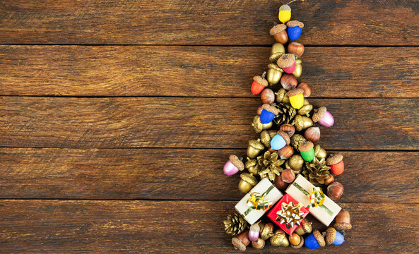 Creative alternative Christmas tree shape made from painted acorns, pine cones, and small gift boxes. Flat lay composition for winter holidays celebration with copy space for text