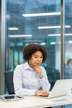 Businesswoman working on laptop in office, professional woman using computer for financial analysis and corporate tasks at desk with focus and concentration