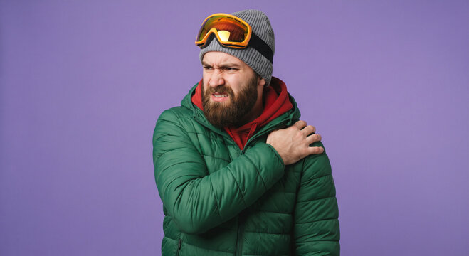 Man feeling shoulder pain or stiffness wearing winter jacket and goggles