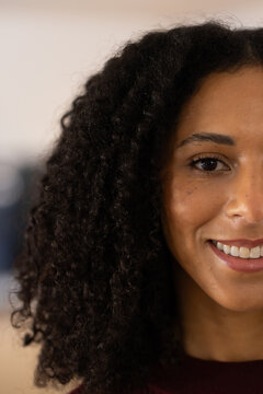African American woman smiling slightly, showing freckles and full curly hair in studio