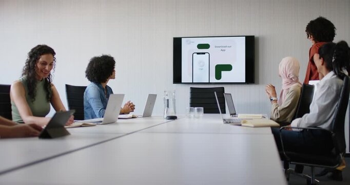Female team watching app slide, causing presenter standing, adjusting laptop and demoing app