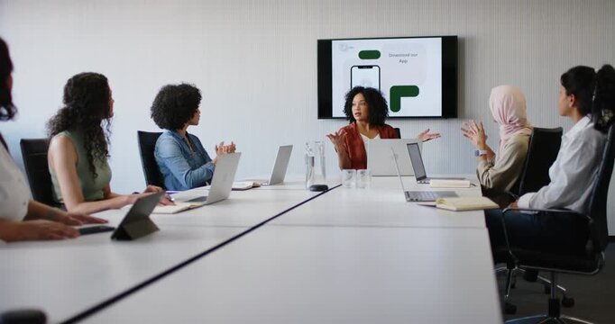 African American woman leading phone mockup with Download prompt at long table, promoting downloads