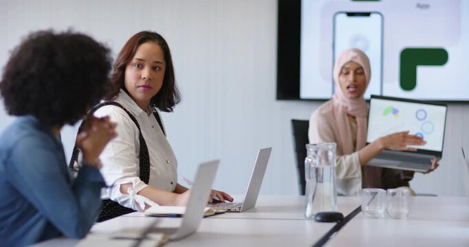 African American woman raising laptop after gesture pointing to app mockup seeking input in office