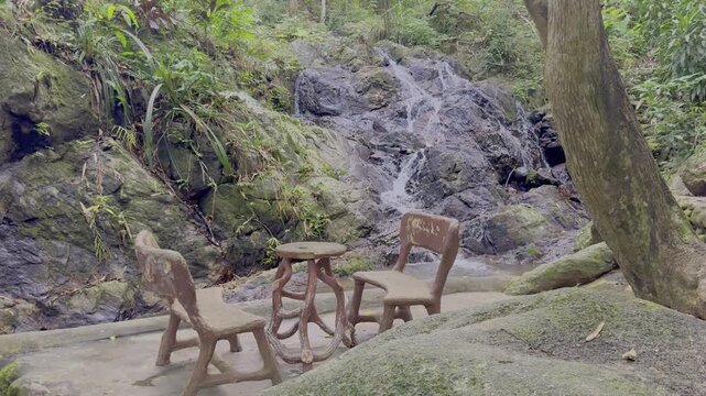 Kathu Dam waterfall water gently flowing down the rocks surrounded by lush green trees flowers and tables Patong on the Island of Phuket Thailand