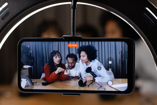 African American collaborators recording at studio table with smartphone, ring light, microphone