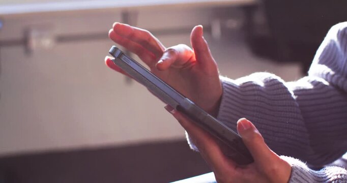 Right hand lowering from hover tapping, swiping tablet near window as left hand steadying