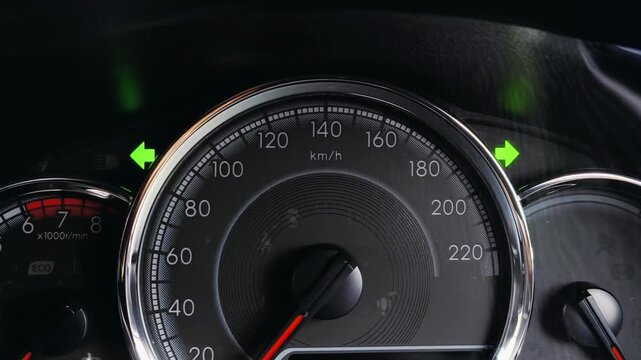 Close-up view of car instrument cluster showing active green turn signal arrow indicators on speedometer