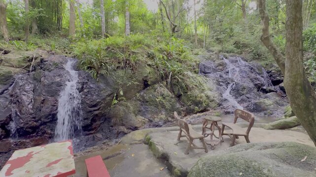 Kathu Dam waterfall water gently flowing down the rocks surrounded by lush green trees flowers and tables Patong on the Island of Phuket Thailand