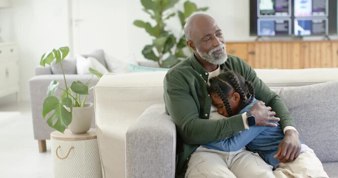 African father and child sitting on gray sofa father cradling after child burying face for comfort