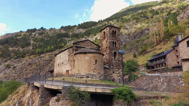 Church of Sant Joan de Caselles, a medieval Romanesque church in Andorra, featuring a stone bell tower and rounded apse surrounded by forested Pyrenees mountains