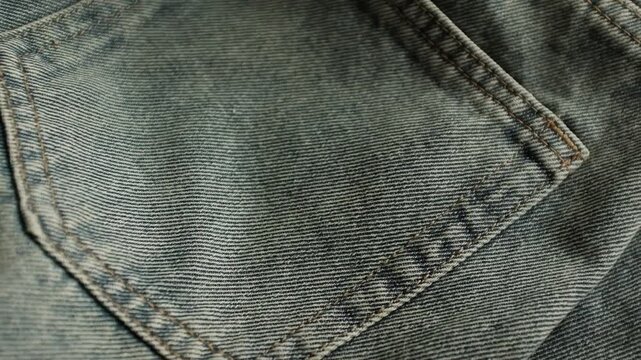 Close-up macro shot of detailed textured weave, folds, and soft twill lines of dark grey denim fabric. For stylish background, fashion presentations, textile manufacturing, clothing store commercials.
