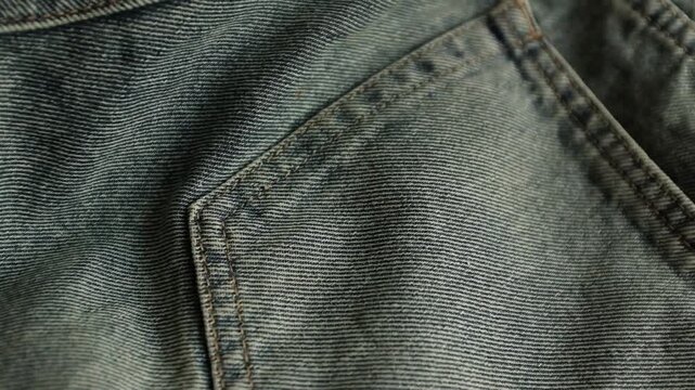 Close-up macro shot of detailed textured weave, folds, and soft twill lines of dark grey denim fabric. For stylish background, fashion presentations, textile manufacturing, clothing store commercials.