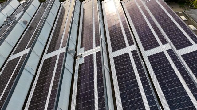 4k Aerial view solar panel facade on modern high rise with bright sun flare, glass and metal surfaces, strong geometric lines, clean energy architecture