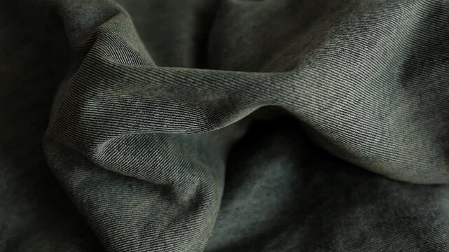 Close-up macro shot of detailed textured weave, folds, and soft twill lines of dark grey denim fabric. For stylish background, fashion presentations, textile manufacturing, clothing store commercials.