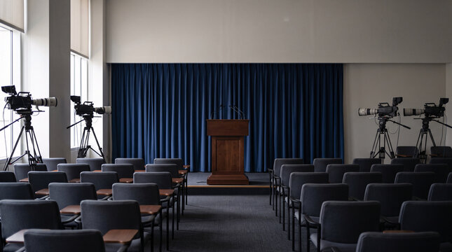 Salle de conf&eacute;rence de presse vide avec podium, micros et cam&eacute;ras