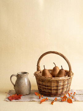 Thanks giving poster with text space, A rustic wicker basket overflows with ripe, golden pears, accompanied by a ceramic pitcher and scattered autumn leaves,