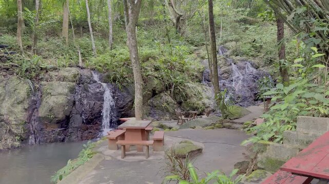Kathu Dam waterfall water gently flowing down the rocks surrounded by lush green trees flowers and tables Patong on the Island of Phuket Thailand