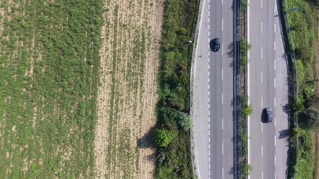 Highway Traffic and Fields: An aerial view showcases a dual carriageway with cars traveling in both directions, bordered by agricultural fields under a bright sky.