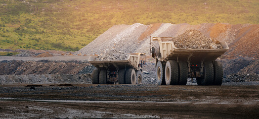 Two heavy dump trucks in quarry at sunset for industrial background mining © Parilov