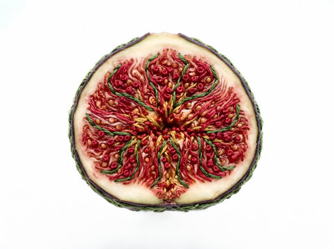 Fresh red fig cut in half showing vibrant interior seeds and flesh, isolated on white background