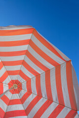 Obraz premium One striped beach umbrella under blue sky, bottom view