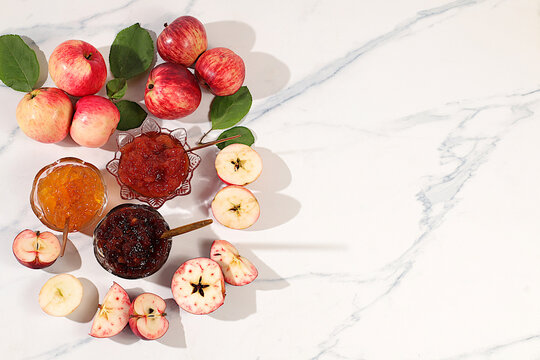 An assortment of preserves, fruit butters and fresh fruit purees arranged on a concrete kitchen counter.Fresh apple butter or jam made from various apple varieties. home canning concept, banner