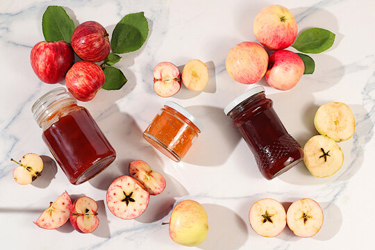 Fresh apple butter or jam made from various apple varieties. An assortment of preserves, fruit butters and fresh fruit purees arranged on a concrete kitchen counter.home canning concept, banner
