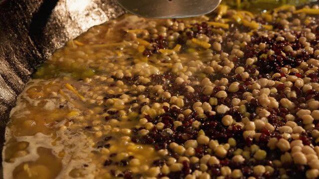 Cooking the base for Uzbek wedding plov as chickpeas, raisins and spices simmer in a huge kazan. Traditional food preparation reflects Uzbekistan's cuisine, hospitality and culinary tourism
