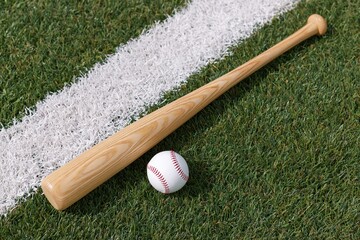 Fototapeta premium The Baseball Bat Resting On Green Field Beside White Line