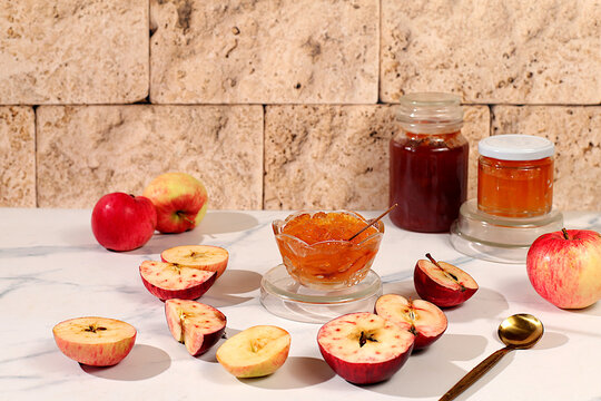 Fresh apple butter or jam made from light colored apple varieties. Jars of preserves, fruit butter, and fruit pur es arranged on a concrete kitchen countertop. Concept of homemade preserves,